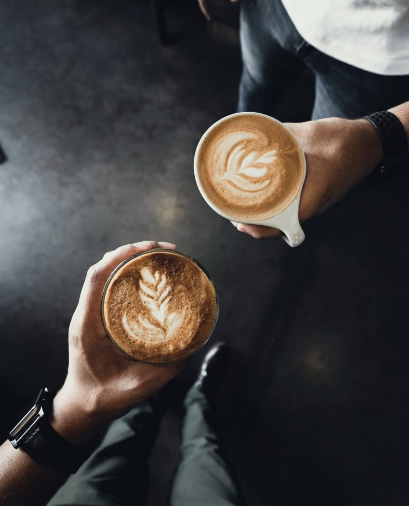 two people holding to different coffee drinks