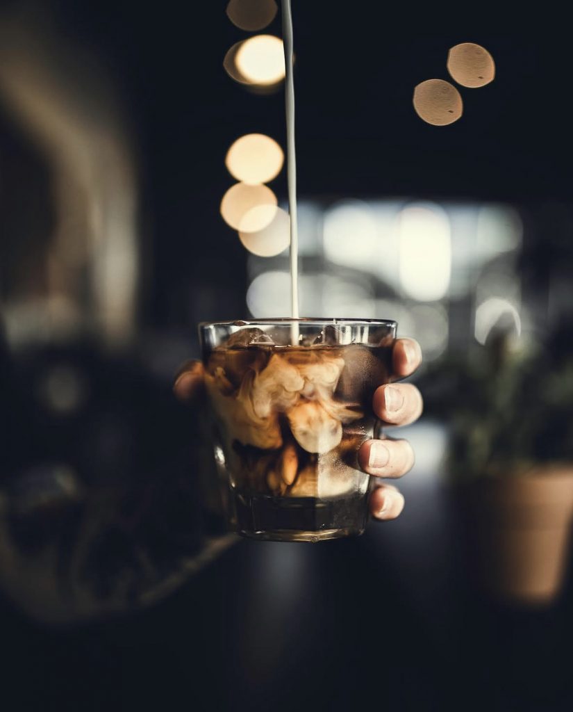 pouring milk over iced coffee